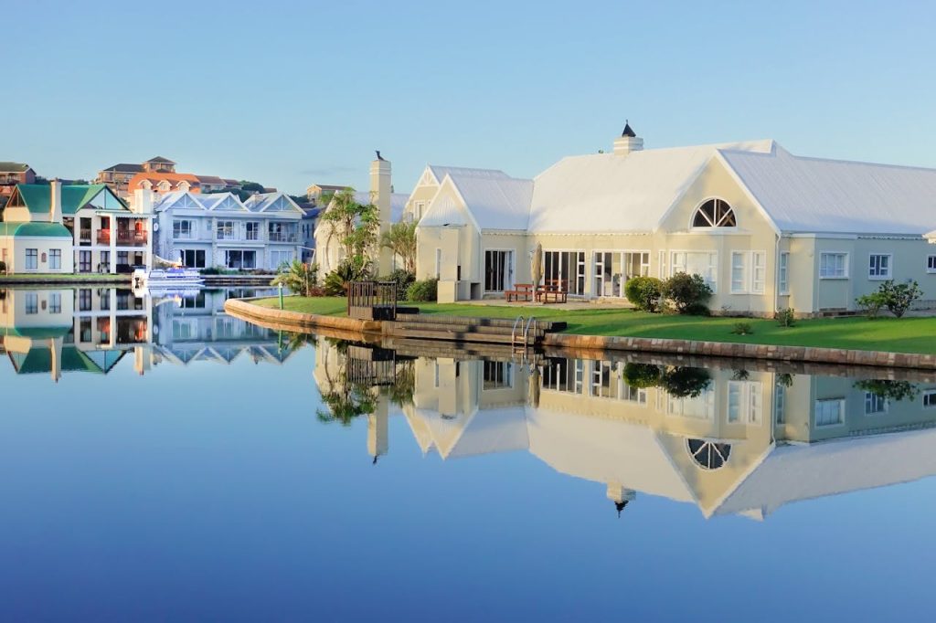 Serene view of elegant waterfront villas with perfect reflection on calm water.